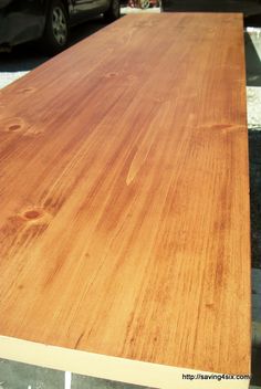 a large wooden table sitting on top of a parking lot next to a parked car