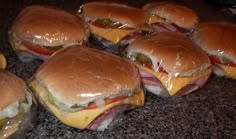 several hamburgers with cheese and pickles on them sitting on a counter top next to some ketchup