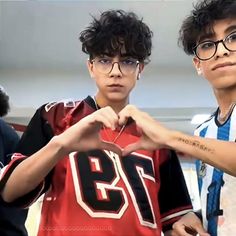 two young boys wearing glasses and holding up a shirt with the number twenty on it