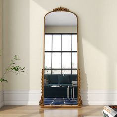 a mirror sitting on top of a wooden floor next to a table with a plant