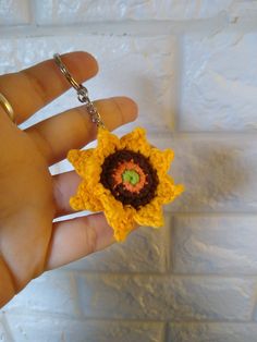 a hand holding a tiny crocheted flower keychain