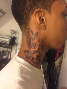 a person with a bird tattoo on their neck and behind his ear, looking to the side