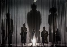 silhouettes of people standing in front of a curtain with light coming from behind them