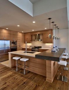 a modern kitchen with wooden floors and stainless steel appliances, including an island countertop