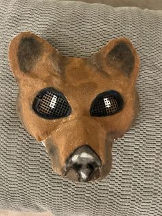 an animal mask with two eyes on top of a couch