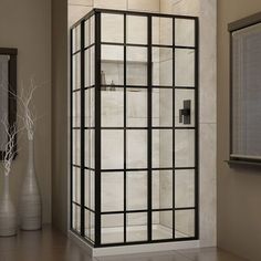 a bathroom with a stand up shower next to a mirror and vase on the floor