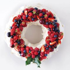 a cake decorated with berries and holly leaves