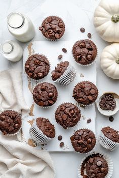 chocolate muffins on a white tray next to pumpkins and other food items