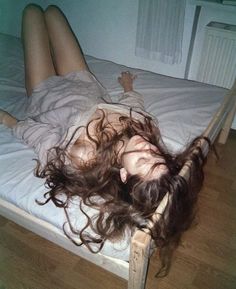 a woman laying on top of a bed with long hair