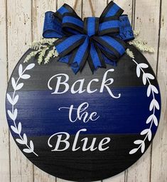 a wooden sign that says back the blue on it with a bow hanging from it's side