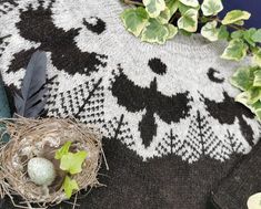 a bird's nest sits on top of a black and white knitted blanket