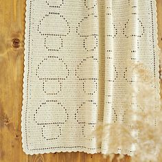 a white crocheted blanket hanging on a wooden wall next to a potted plant