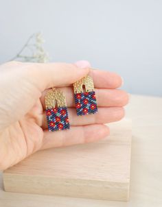 a person holding some kind of earrings in their hand on top of a wooden table