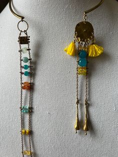 The upper part, a solid piece of brass is the choker part from which two separate medallions are suspended. One has a ladder like effect with stone beads replacing the ladder rungs. The second starts with a tasseled accent with chains suspended from it with some intermittent rungs. Bohemian Beaded Necklaces With Gemstone Beads, Artisan Gold Necklace With Dangling Beads, One Of A Kind Brass Dangle Jewelry, Bohemian Gold Beaded Chain Jewelry, Bohemian Gold Jewelry With Beaded Chain, Artisan Gold Jewelry With Beaded Chain, Gold Metal Jewelry With Gemstone Beads, Fusion Style Festival Jewelry With Natural Stones, Fusion Style Natural Stones Jewelry For Festivals