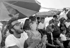 a man holding a baby in his arms while standing next to a group of people