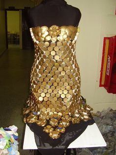 a mannequin made out of gold coins sitting on top of a white table