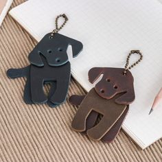 two dog shaped key chains sitting on top of a notebook