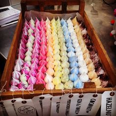 a wooden box filled with lots of different colored marshmallows next to each other