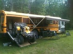 a yellow bus parked in the grass next to a picnic table and chair set up