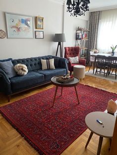 a living room filled with furniture and a red rug on top of a hard wood floor