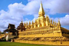 a large golden building sitting on top of a lush green field under a blue sky