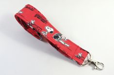 a red keychain with snoopy peanuts on it is sitting on a white surface