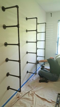 a man laying on the ground in front of some pipes and ladders that are being installed