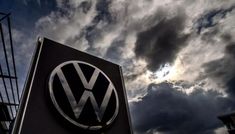 the vw logo is shown on top of a sign in front of cloudy skies