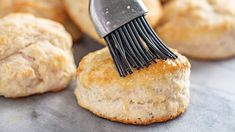 a close up of a pastry being brushed with a brush on top of the biscuits