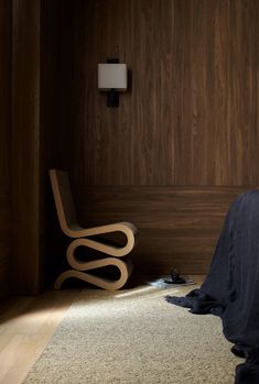 a bedroom with wood paneling and a chair in the corner on the carpeted floor