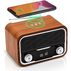 an alarm clock radio sitting on top of a wooden table next to a cell phone