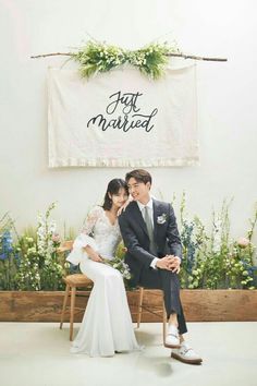 a newly married couple sitting on a wooden bench in front of a sign that says just married