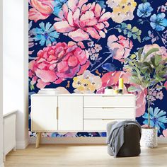 a floral wallpaper with pink, blue and yellow flowers on the sideboard next to a white chest of drawers