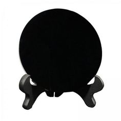 a black table with two legs and a round object on the top, sitting in front of a white background