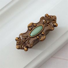 an antique door handle with a green glass in the center on a white wall background