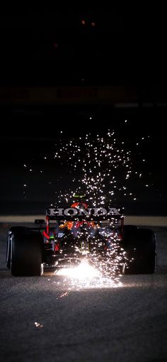 a red bull racing car on the track with fireworks coming out of it's tires