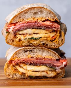 two sandwiches stacked on top of each other with meat, cheese and vegetables in between