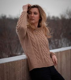 a woman leaning against a wall with her hand on her head and looking at the camera