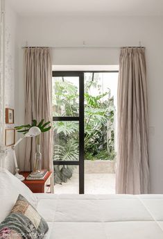 a bed sitting in a bedroom next to a window with curtains on top of it