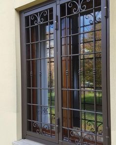 two windows with iron bars on the sides and one window has glass panes that look like filigrees