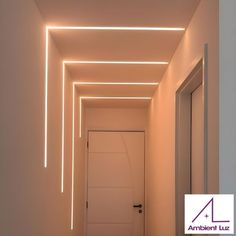 an empty hallway with white walls and lights on the ceiling, leading to another room