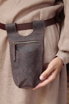 a person holding a brown leather pouch in their hand