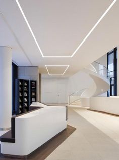 an empty room with white walls and stairs in the center is lit by recessed lights