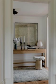 an entryway with a bench, mirror and vases on the table in front of it