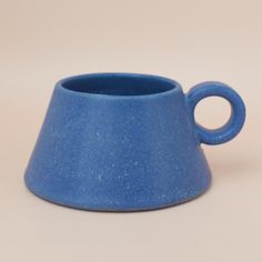 a small blue cup with a handle on the top is sitting in front of a white background