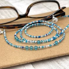 Dainty and bohemian eyeglass necklace chain made with tiny Preciosa Czech crystal seed beads in blue tones and small round faceted cubic zirconia crystals.   Paired with beautiful blue cz gems, this handmade eyeglass chain will definitely create a unique look. This eyeglass lanyard is made on strong quality beading wire with silver plated wire guardians that protect the eyeglass holder grips. The necklace is ended with spring clasps that hold the eyeglass grips and they can be easily removed to Adjustable Glass Necklaces With Tiny Beads, Handmade Adjustable Glasses Chains With Round Beads, Adjustable Glass Beaded Necklaces With Tiny Beads, Adjustable Glass Necklace With Tiny Beads, Adjustable Glass Beaded Necklace With Tiny Beads, Adjustable Tiny Beaded Glass Necklaces, Handmade Adjustable Blue Glasses Chains, Adjustable Tiny Beaded Glass Necklace, Handmade Adjustable Turquoise Glasses Chains