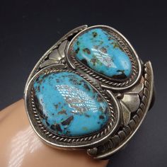 "VINTAGE NAVAJO BRACELET DESCRIPTION: This cuff features a pair of gorgeous Blue Diamond turquoise cabochons. The gemstones are secure in smooth bezel, on a foundation of heavy gauge vintage sterling silver. This bracelet will be a cherished addition to your collection of fine vintage Native American jewelry. MEASUREMENTS: Interior of the cuff measures 5 3/8\" with an additional 1 3/8\" slightly adjustable gap. Total circumference: 6 3/4\" Measures 2 3/8\" straight across the widest part of the Blue Polished Bangle Cuff Bracelet, Blue Oval Vintage Cuff Bracelet, Formal Blue Bracelets With Cabochon, Blue Round Cuff Bracelet For Formal Occasions, Unique Blue Oval Cuff Bracelet, Blue Oval Gemstone Cuff Bracelet, Formal Blue Gemstone Cuff Bracelet, Turquoise Bangle Cuff Bracelet For Formal Occasions, Luxury Blue Cuff Jewelry