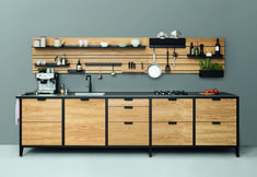 a kitchen with wooden cabinets and black counter tops, hanging utensils on the wall