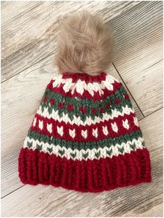 a red and white knitted hat with a pom - pom on top