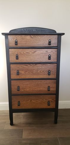 a wooden dresser sitting on top of a hard wood floor next to a white wall